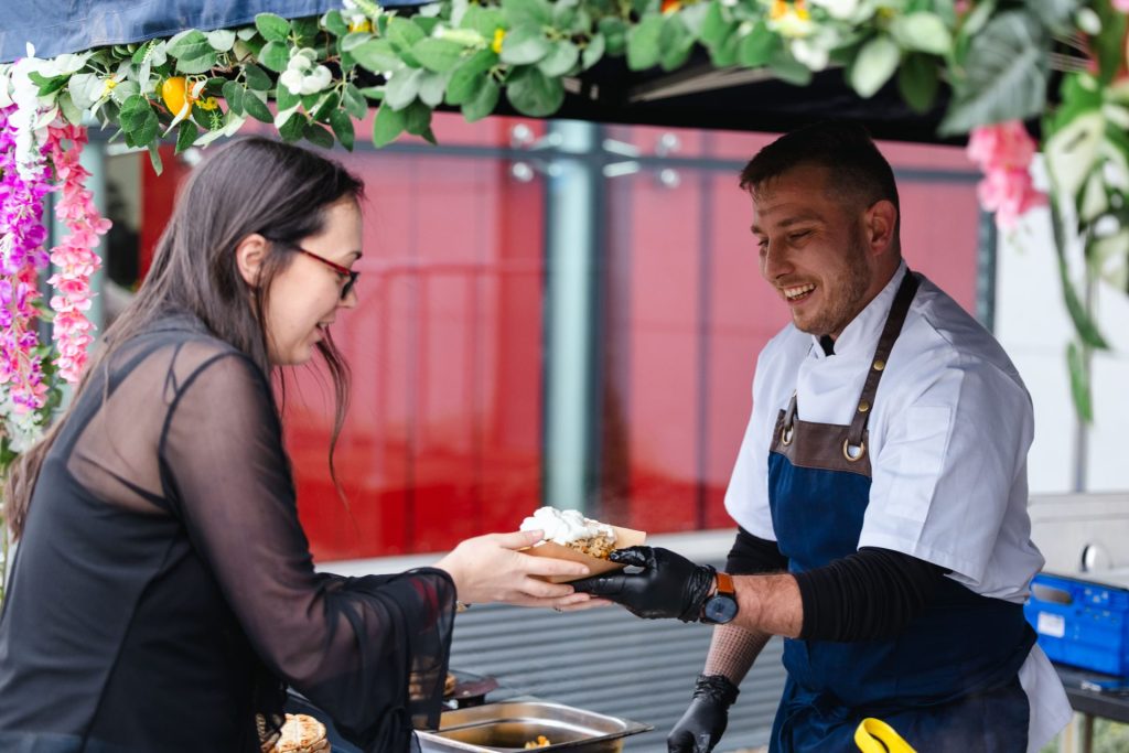 A chef in a white outfit and blue apron preparing greek gyros.